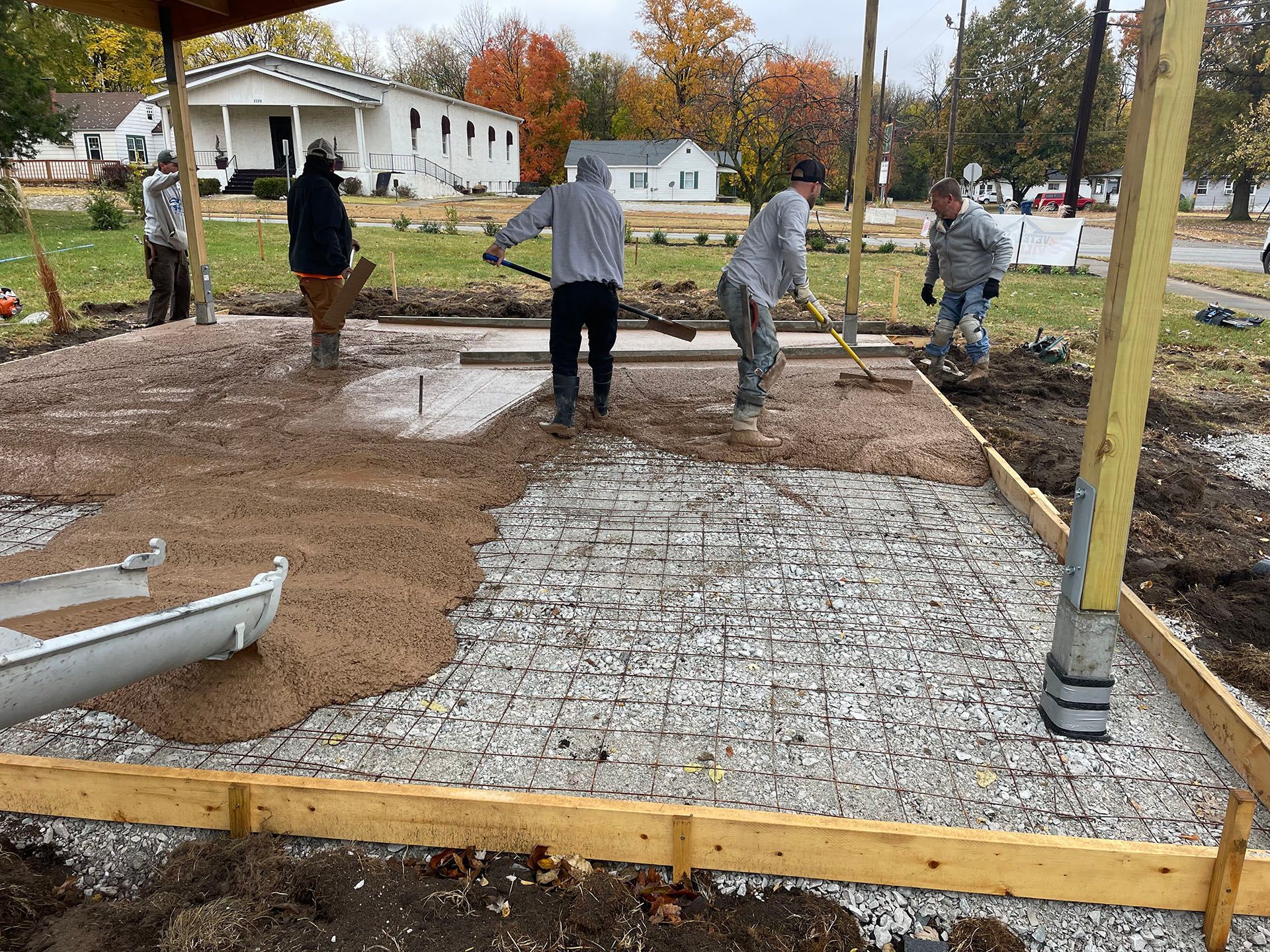 A group of men are working on a concrete driveway.