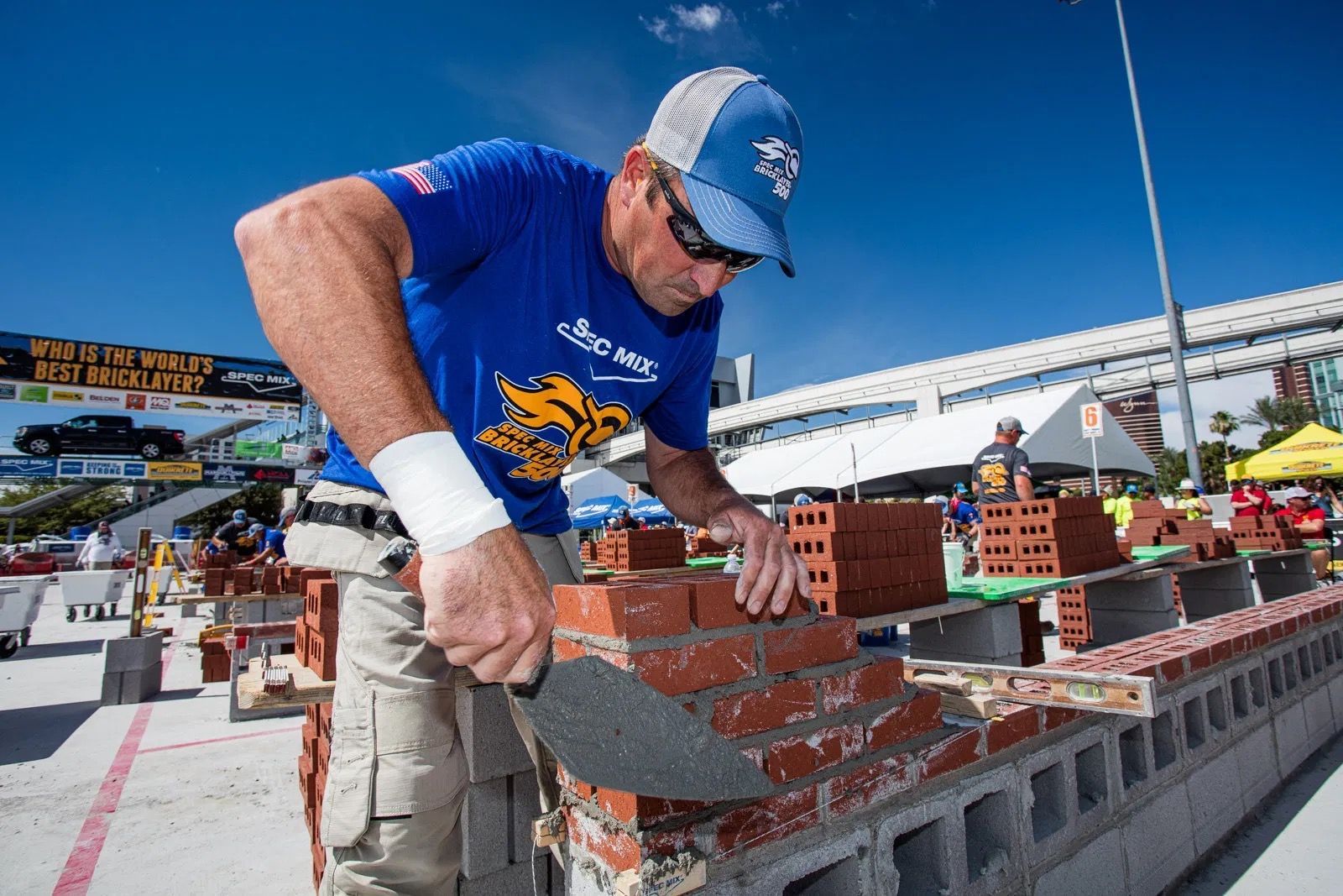 A man in a blue shirt is working on a brick wall