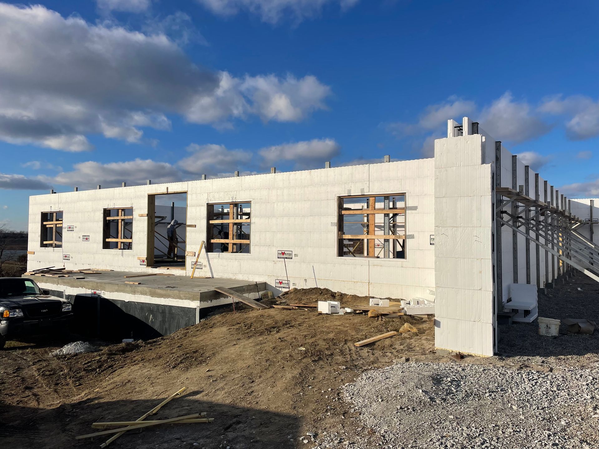A large white building under construction with a blue sky in the background.