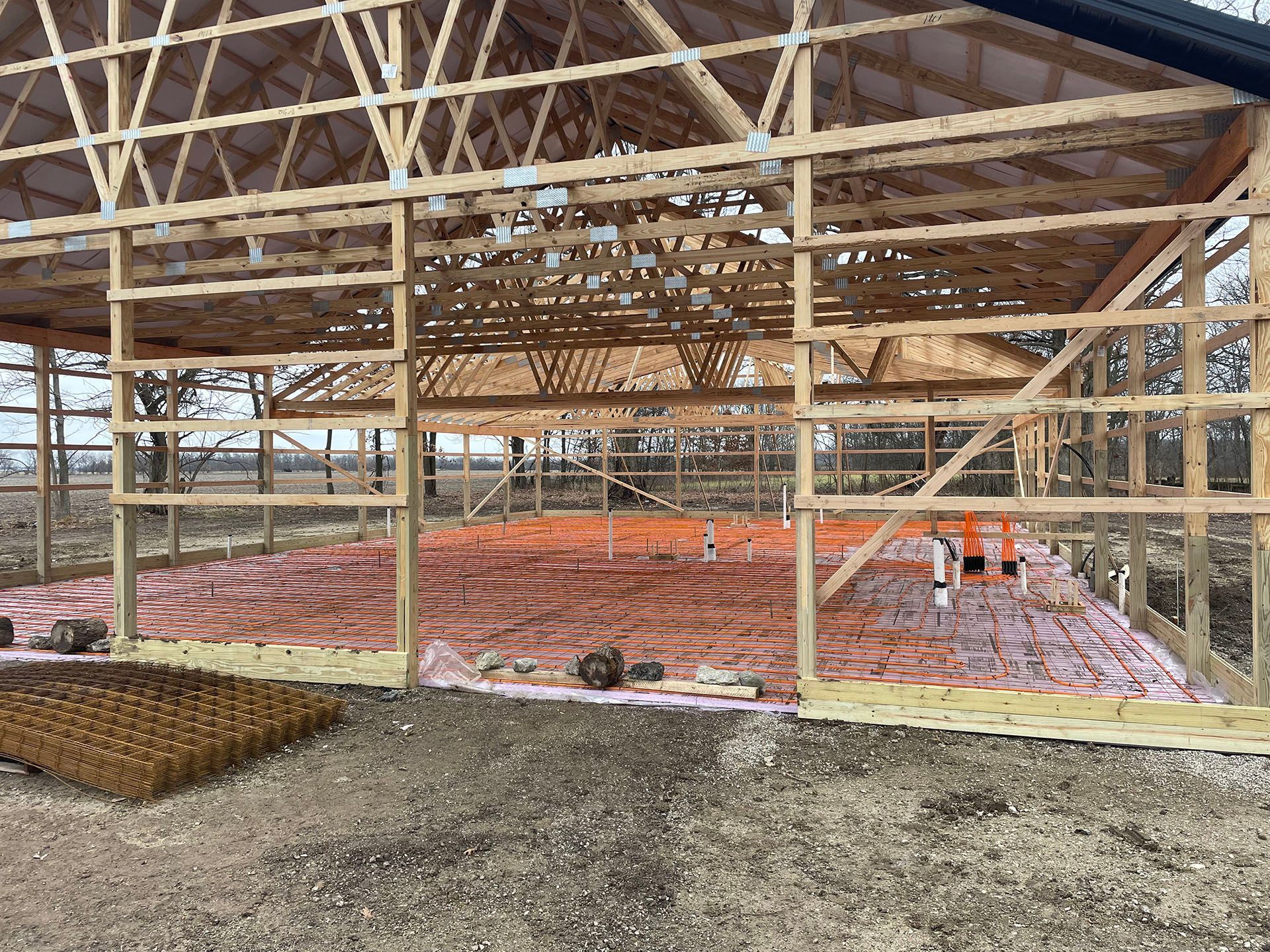 A large wooden building is being built on a dirt field.