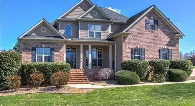 A large brick house with a large lawn in front of it.