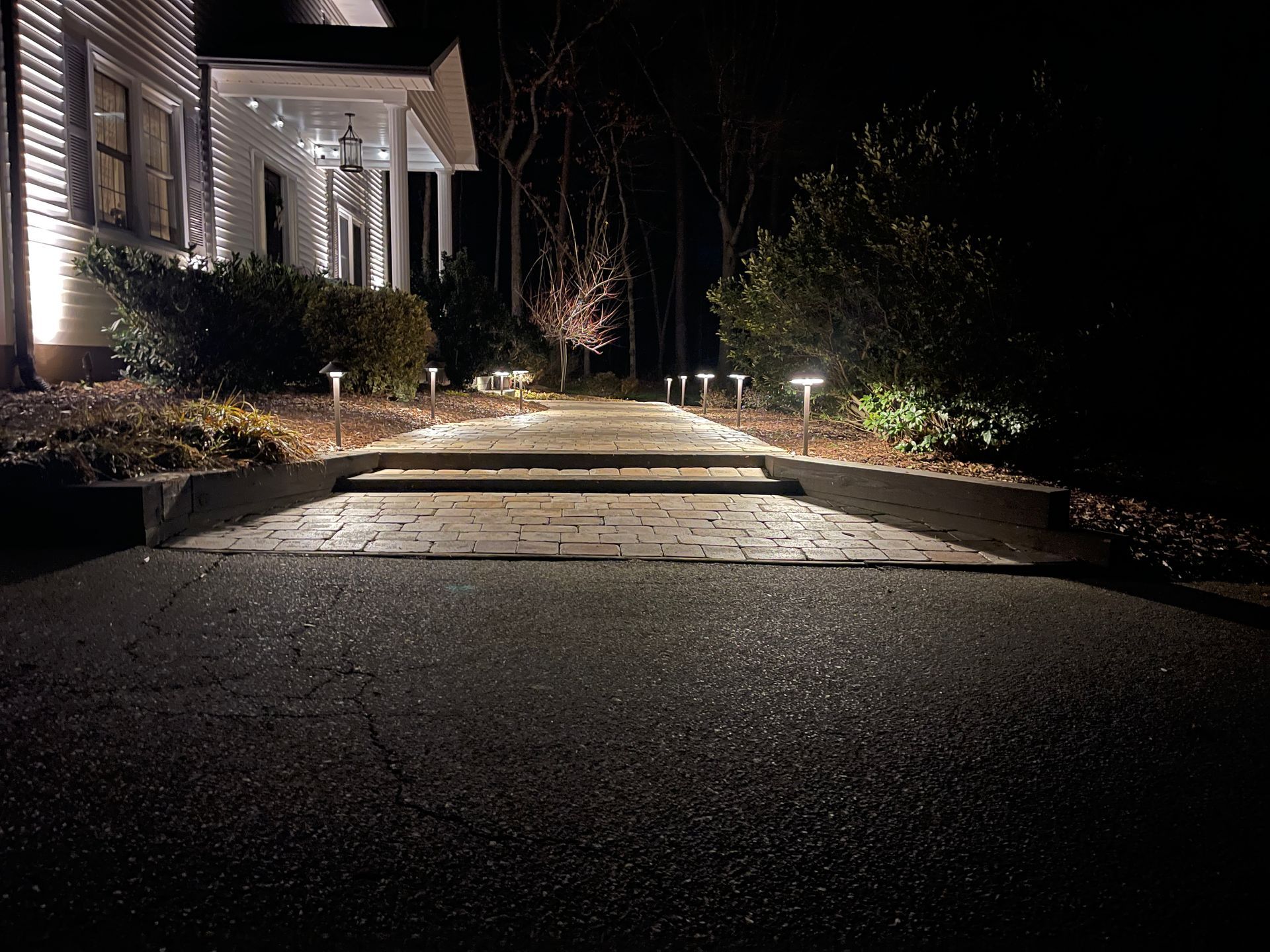 Pathway illuminated by lights leading to a house at night.