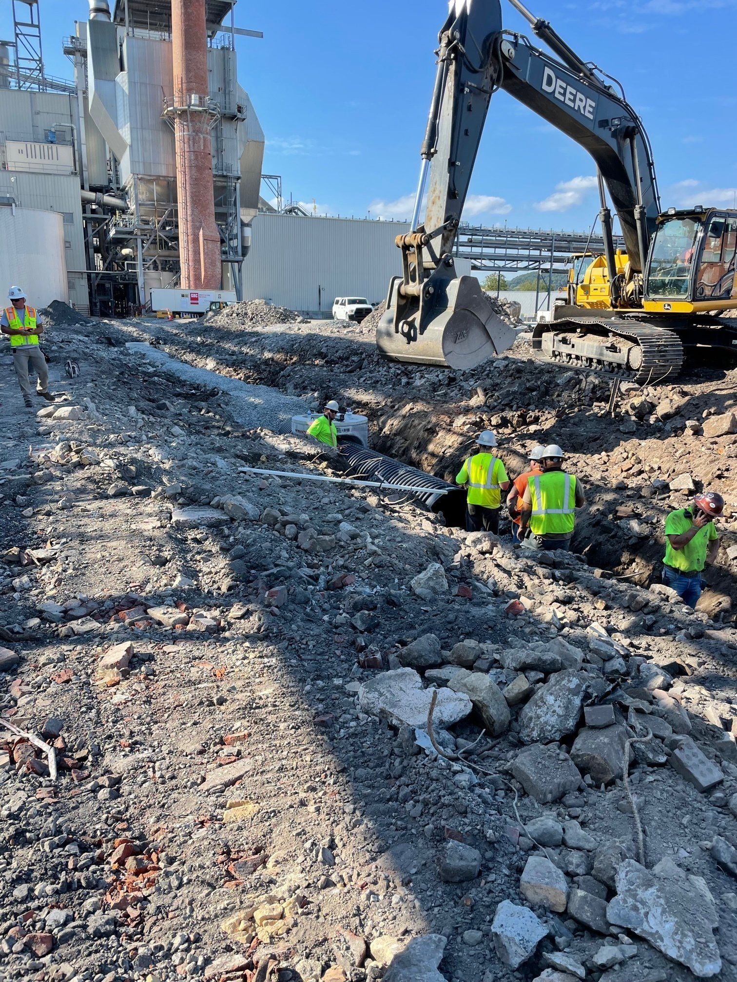 Construction workers installing pipes with the excavator