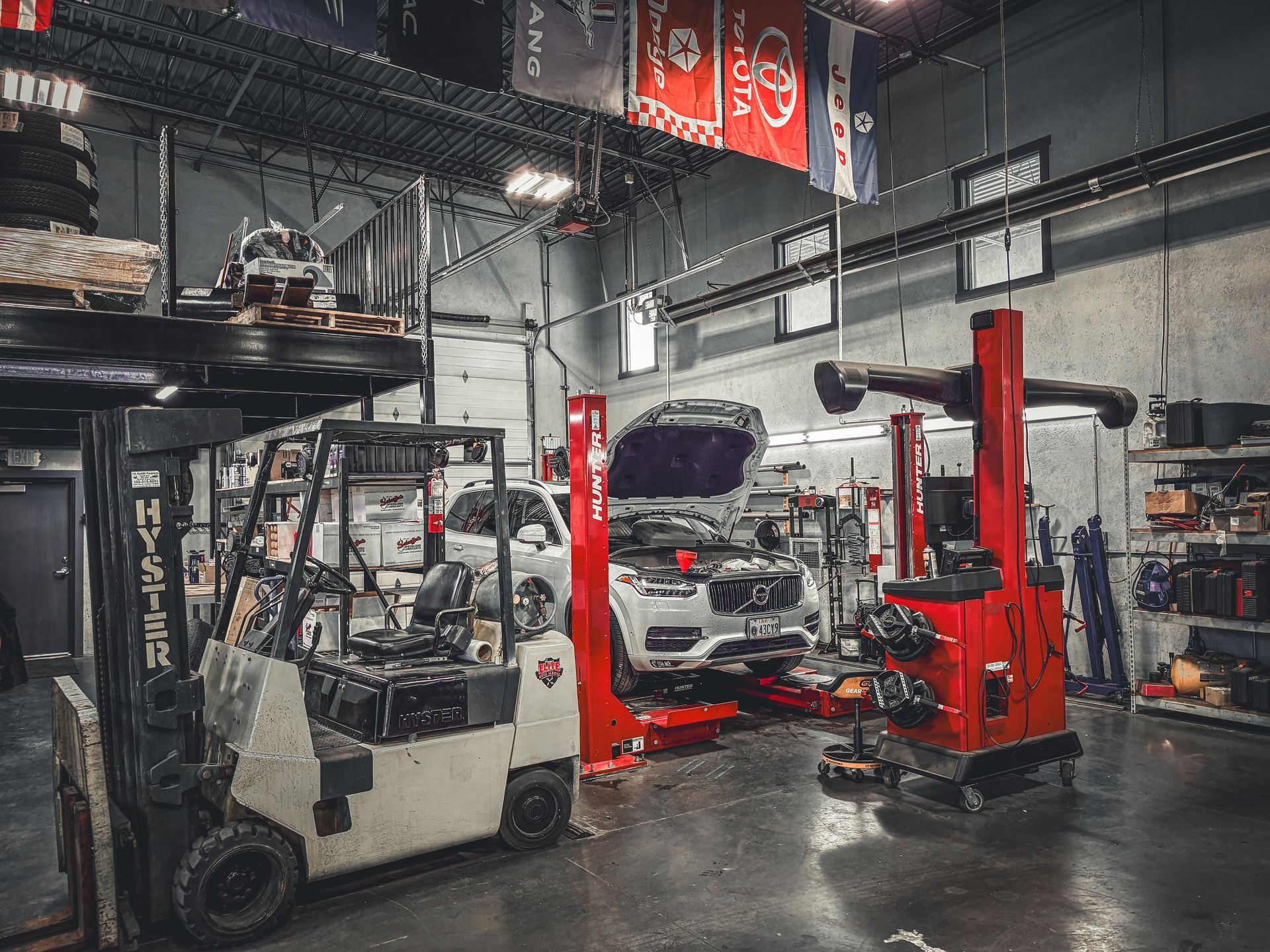 Inside a car repair shop with a forklift and vehicles on lifts.