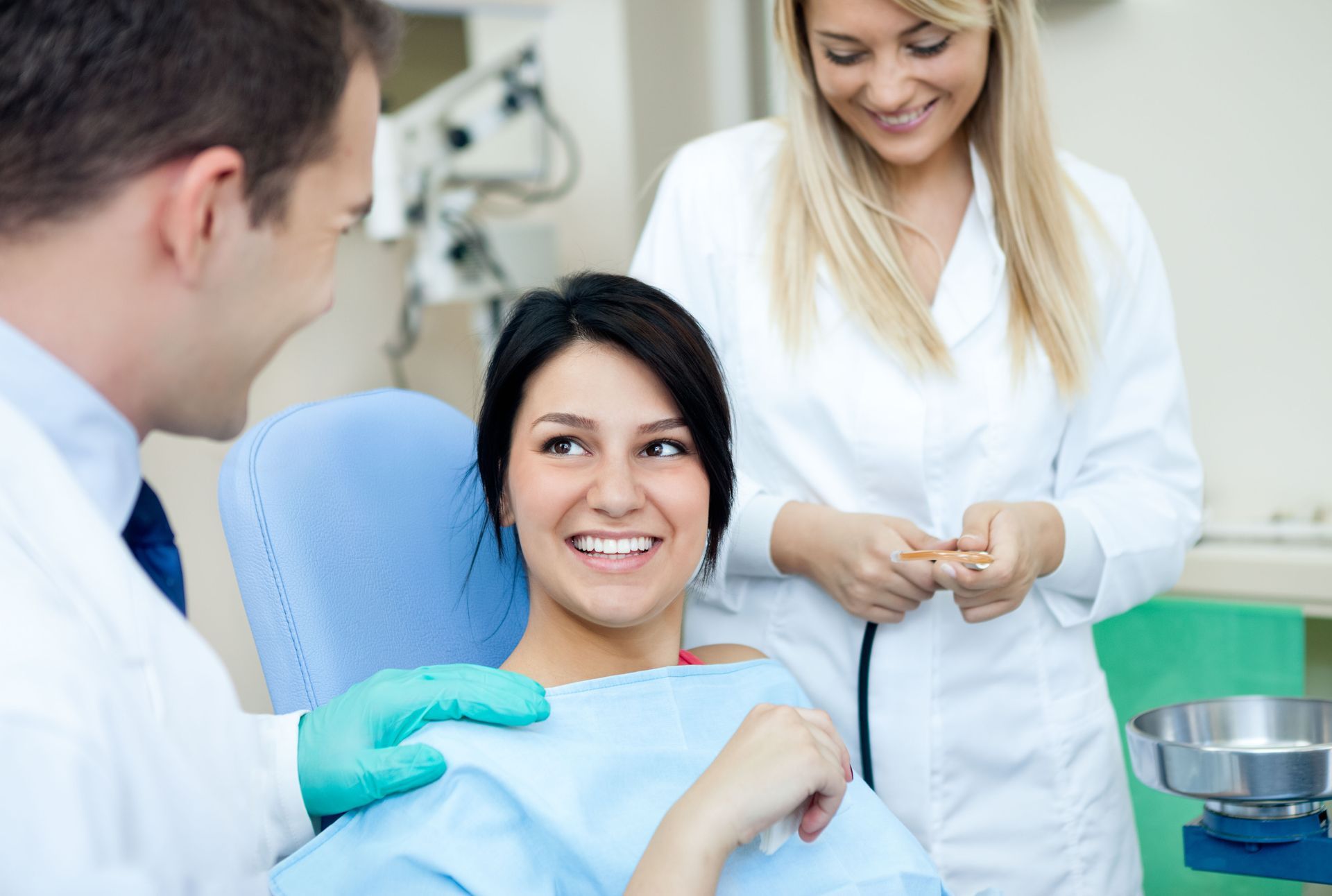 Patient smiling during a dental checkup with dentist and assistant in a clinic