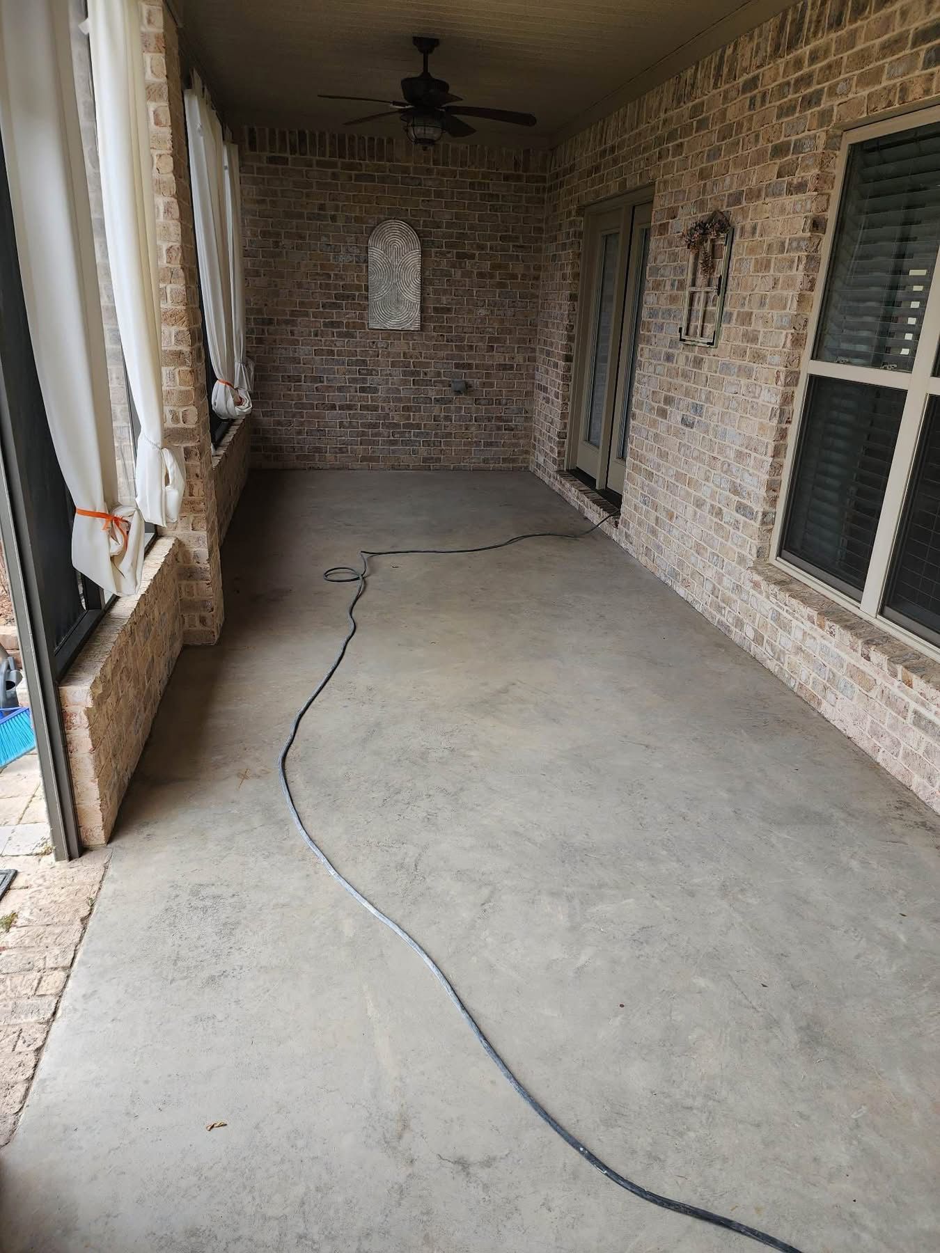 Covered brick porch with a concrete floor and a black cable lying across it