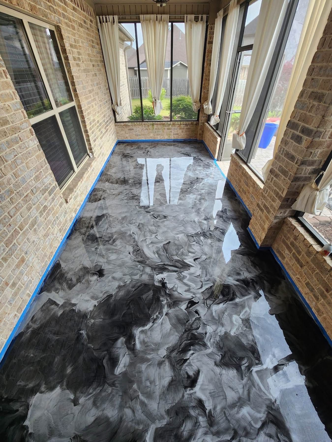 Covered patio with a black-and-gray marbled floor and brick walls, viewed through screened windows.