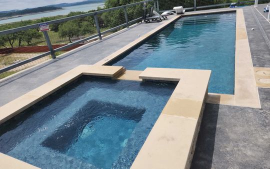 A large swimming pool with a hot tub next to it.