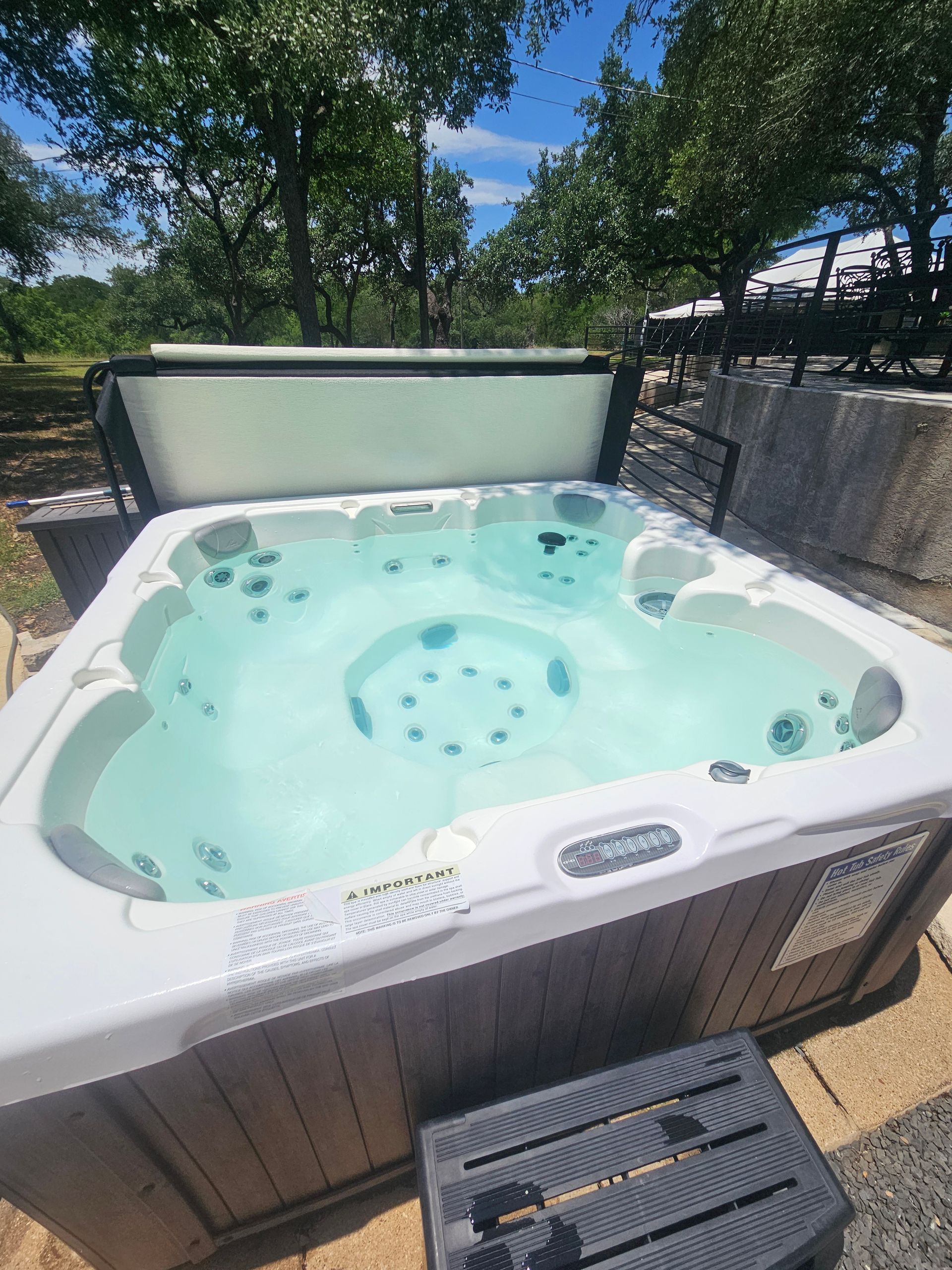 A large white hot tub is sitting on top of a gravel driveway.