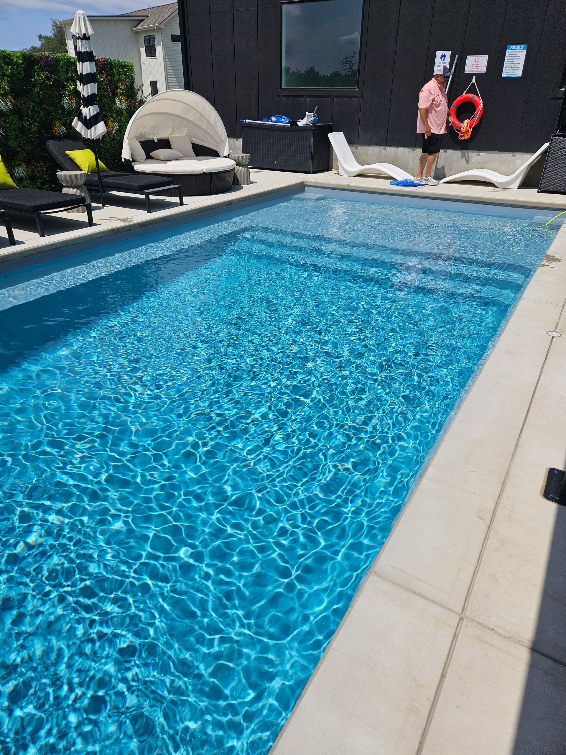 A man is standing next to a large swimming pool.