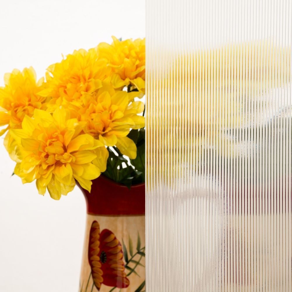 Yellow flowers in a red vase beside frosted glass stripes