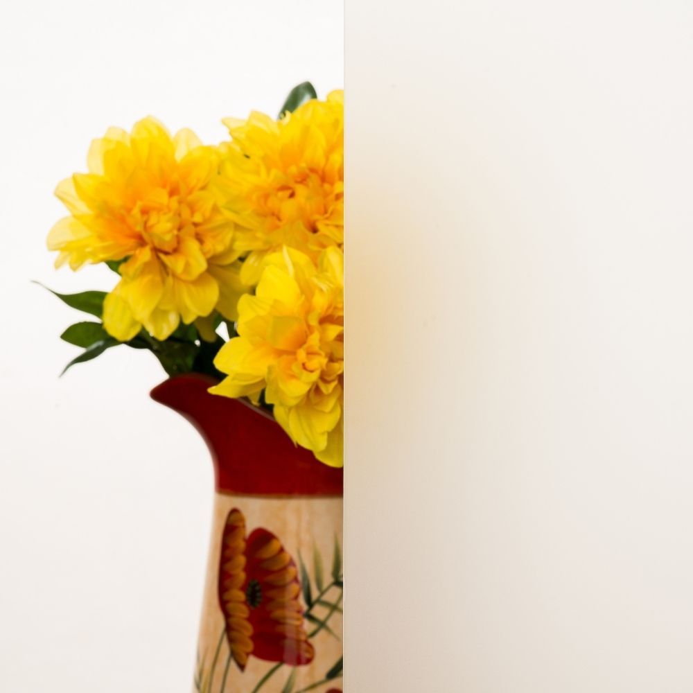 Yellow flowers in a decorative vase against a white background