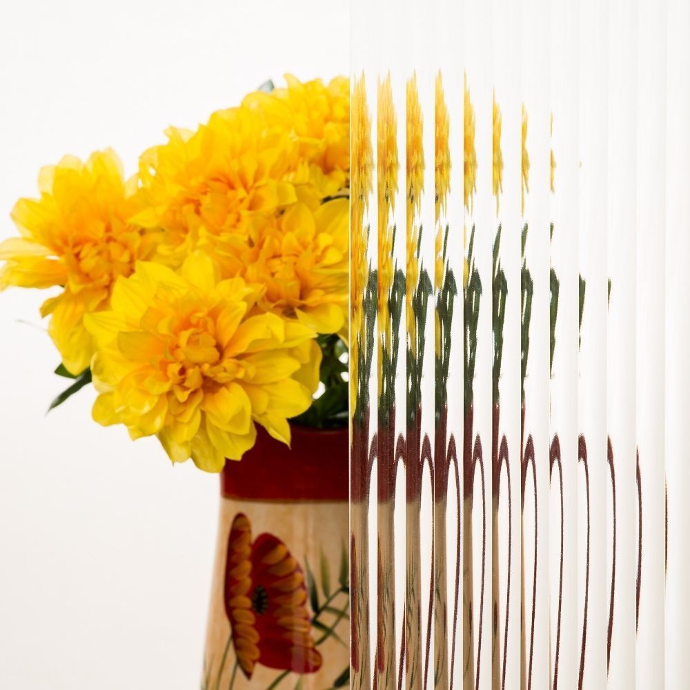 Yellow flowers in a red vase on a white background, with a distorted mirrored effect on the right