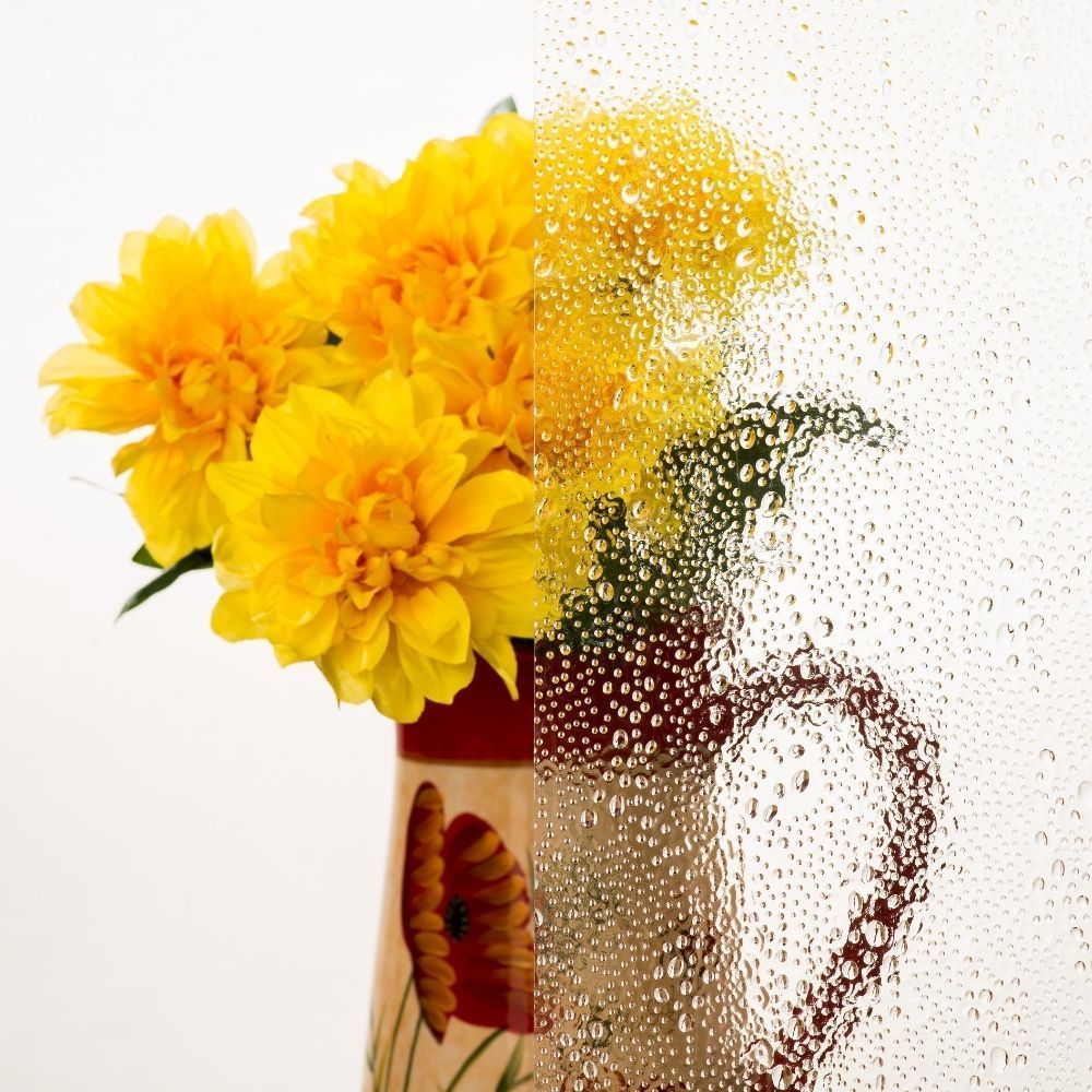 Yellow flowers in a glass pitcher on a white background, partially dissolving into particles