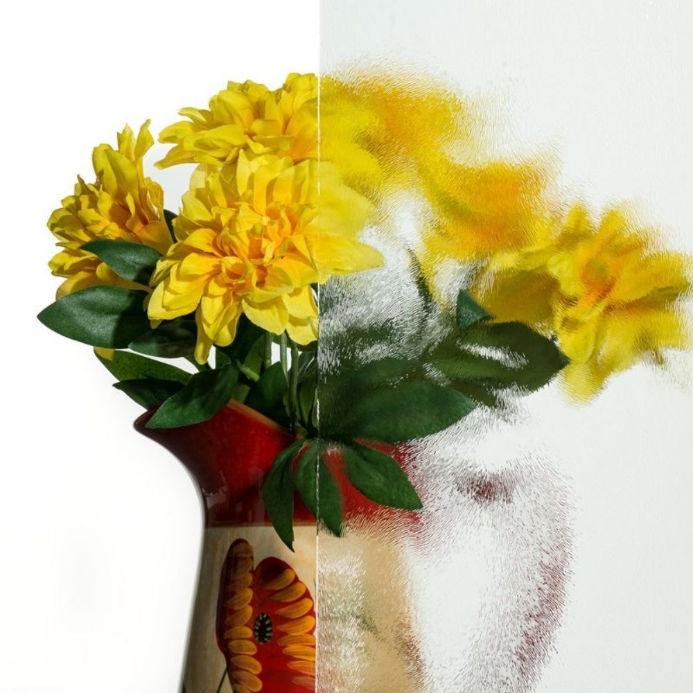 Yellow flowers in a cream vase against a white background, partly dissolving into a pixelated blur