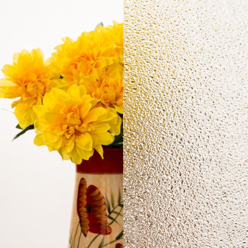 Yellow flowers in a vase beside a textured frosted-glass surface