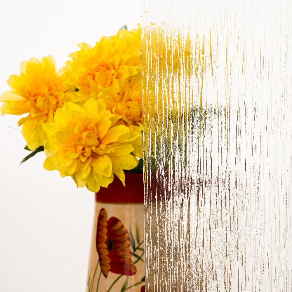 Yellow flowers in a vase with a butterfly design, partially obscured by a white textured overlay