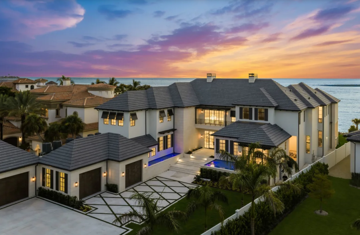 Modern luxury house at sunset with a lit courtyard, pool, and palm trees