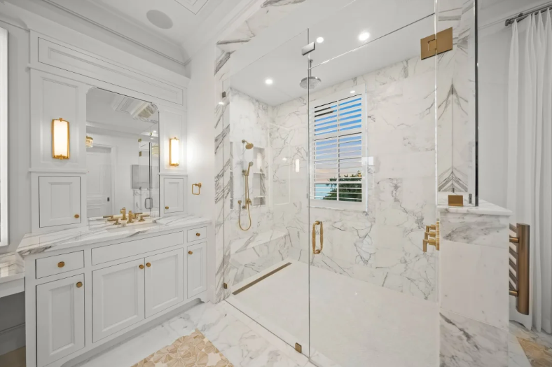 Luxurious white marble bathroom with double vanity, glass shower, and gold accents