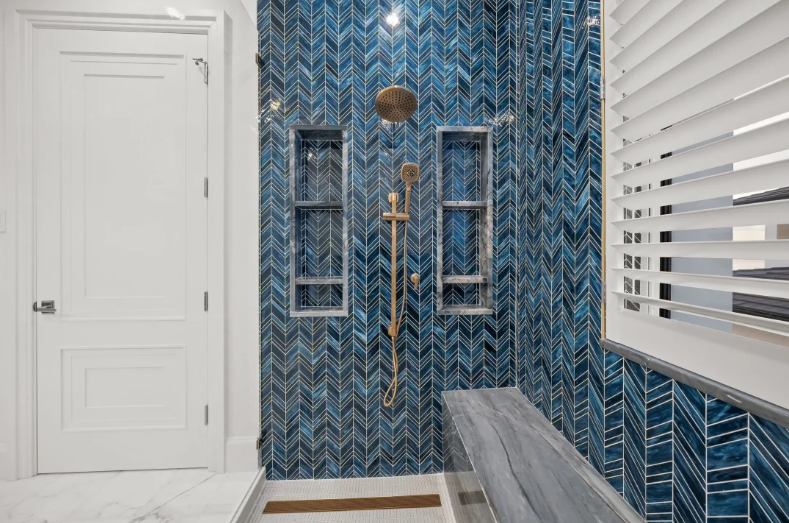 Blue herringbone-tiled porch wall with windows, white door, and bench on a bright exterior patio