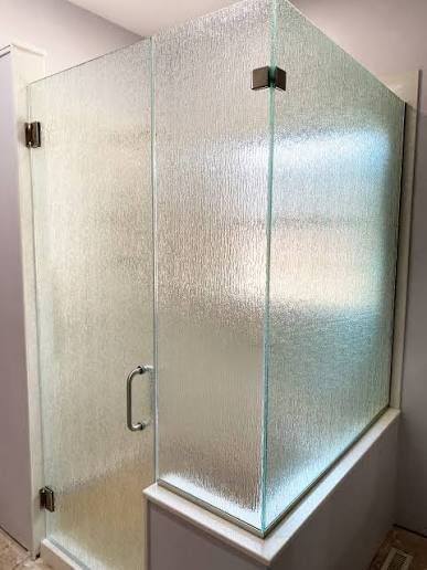 Frosted-glass shower enclosure with hinged door in a bright bathroom