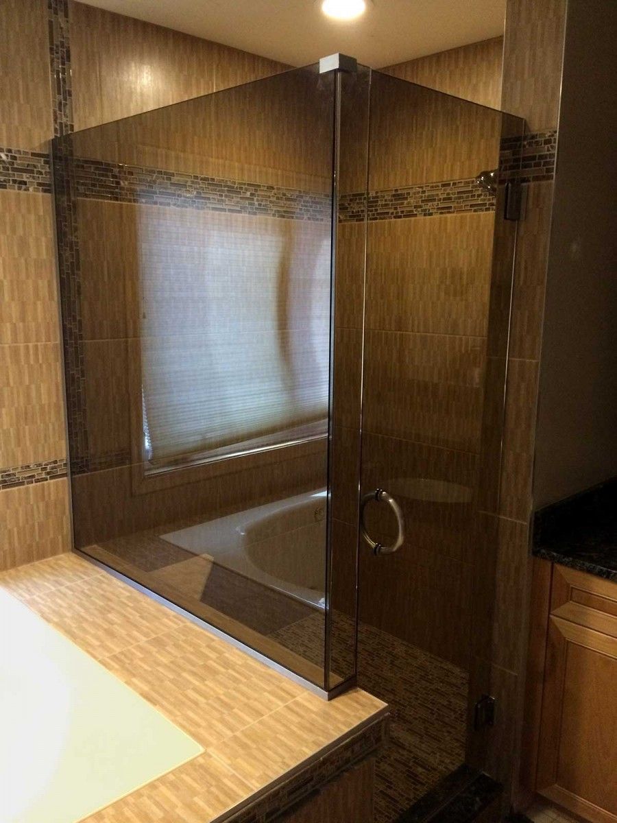 Glass-enclosed shower next to a bathtub and sink in a wood-paneled bathroom