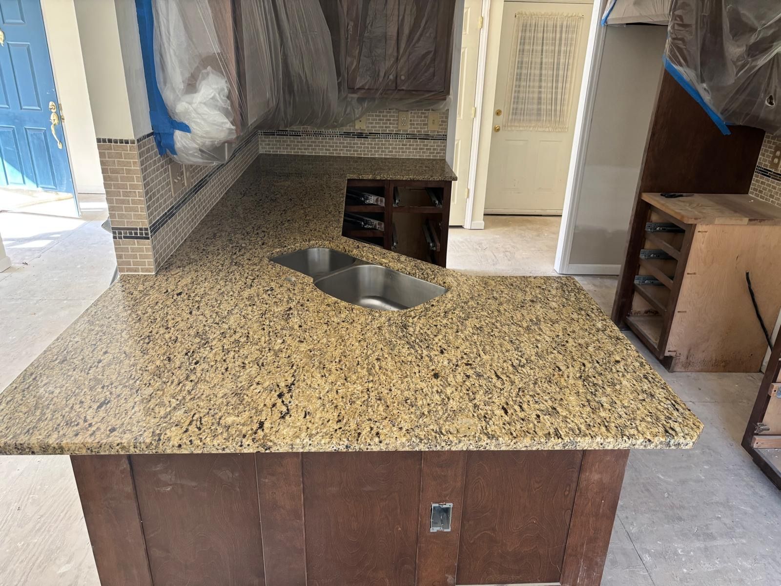 Kitchen island with speckled granite countertop and built-in sink in a tiled room