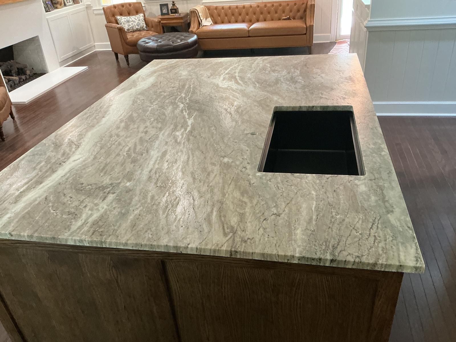 Kitchen island with stone countertop and built-in rectangular sink hole in a modern living space