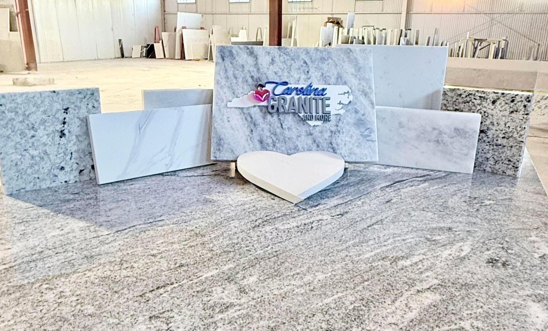 White granite slabs and a heart-shaped stone display in a showroom with a logo centerpiece
