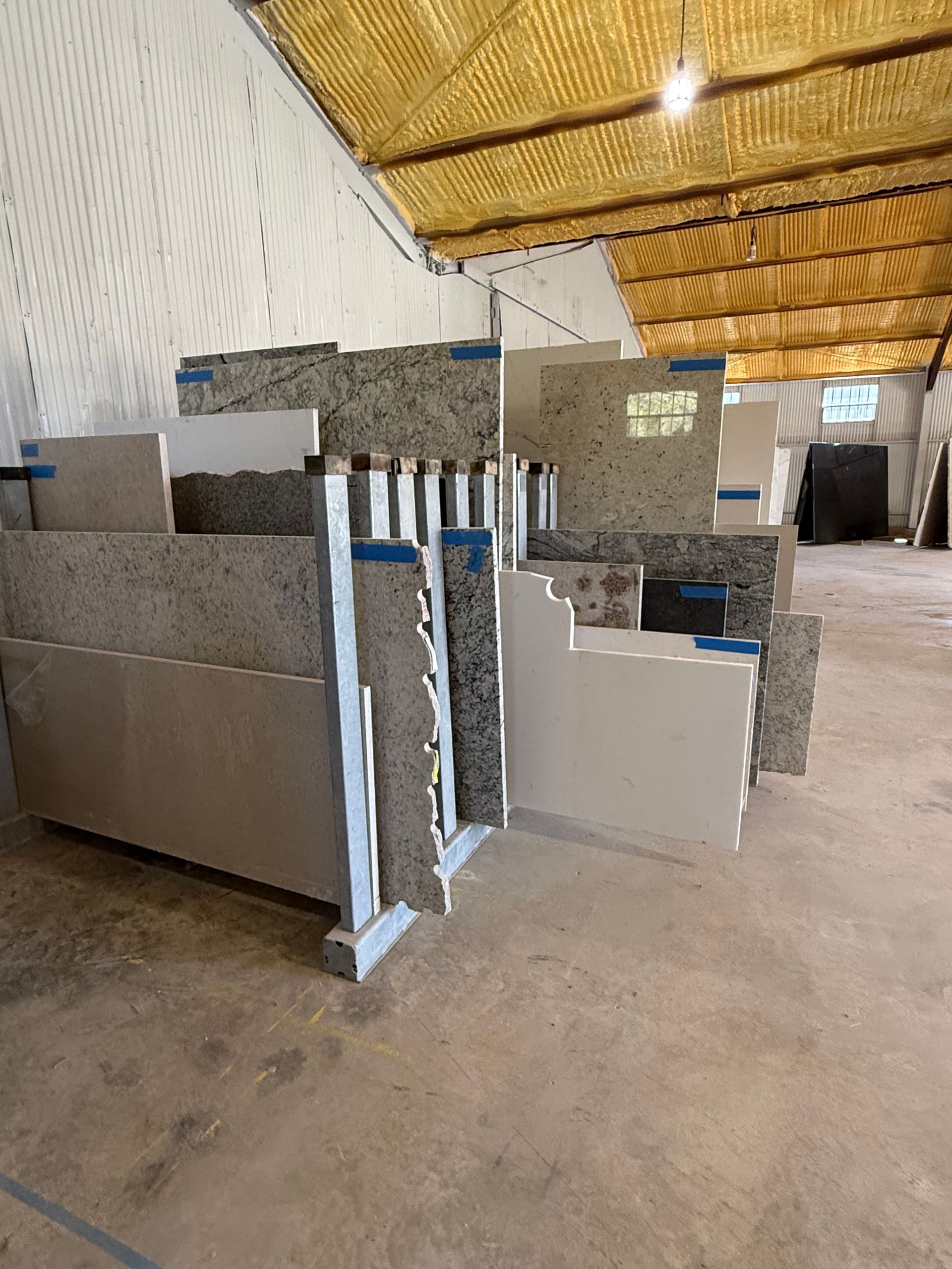 Rows of gray concrete blocks stacked inside a warehouse with a yellow roof