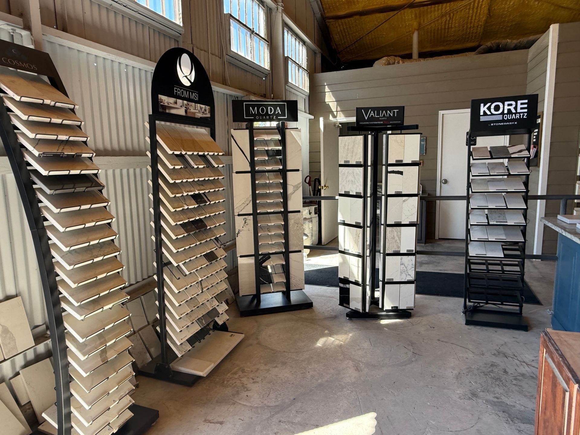 Tile showroom with multiple display racks of flooring samples in a warehouse-like space