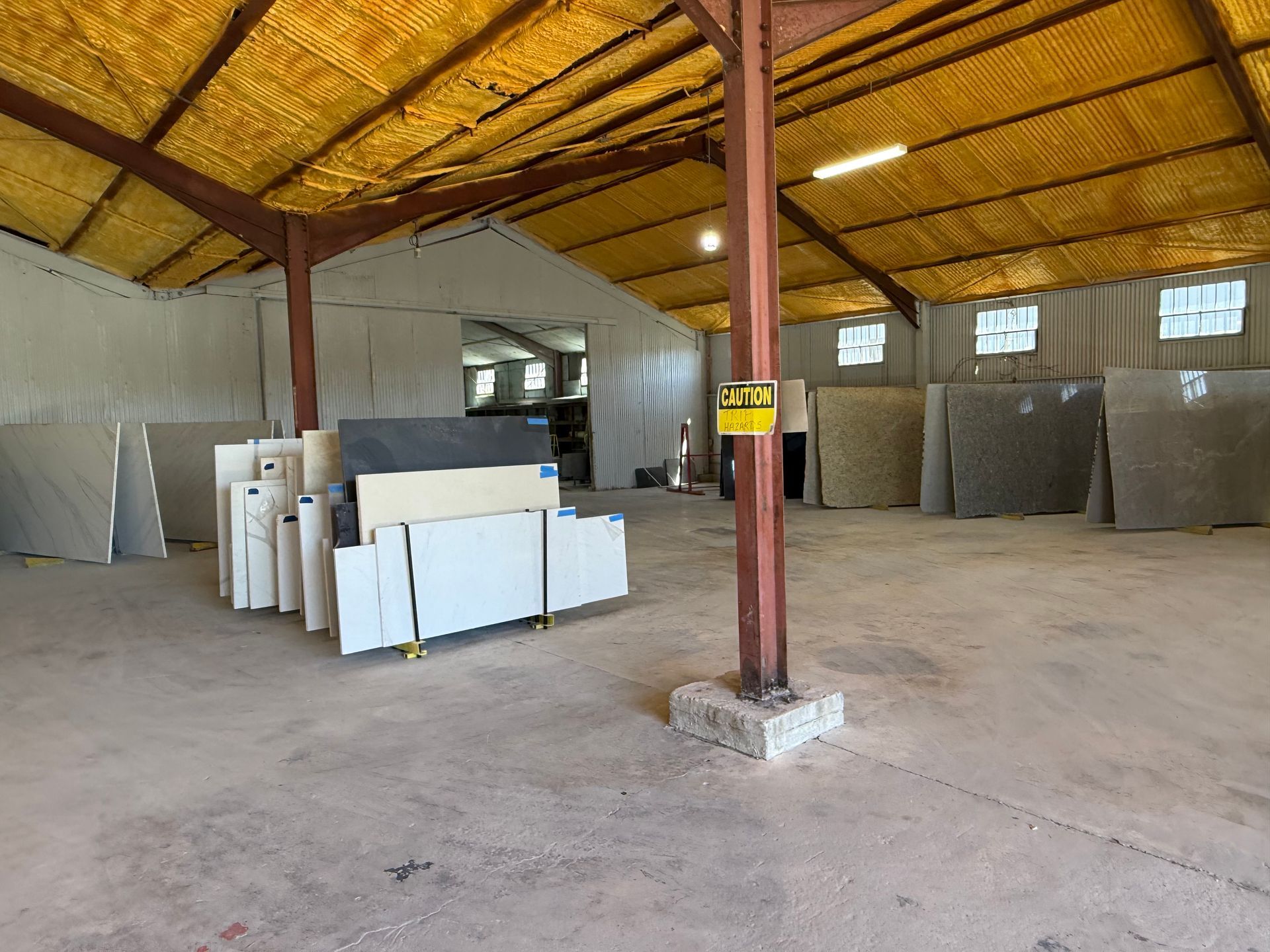 Empty warehouse interior with stacked foam boards, concrete floor, and yellow roof panels