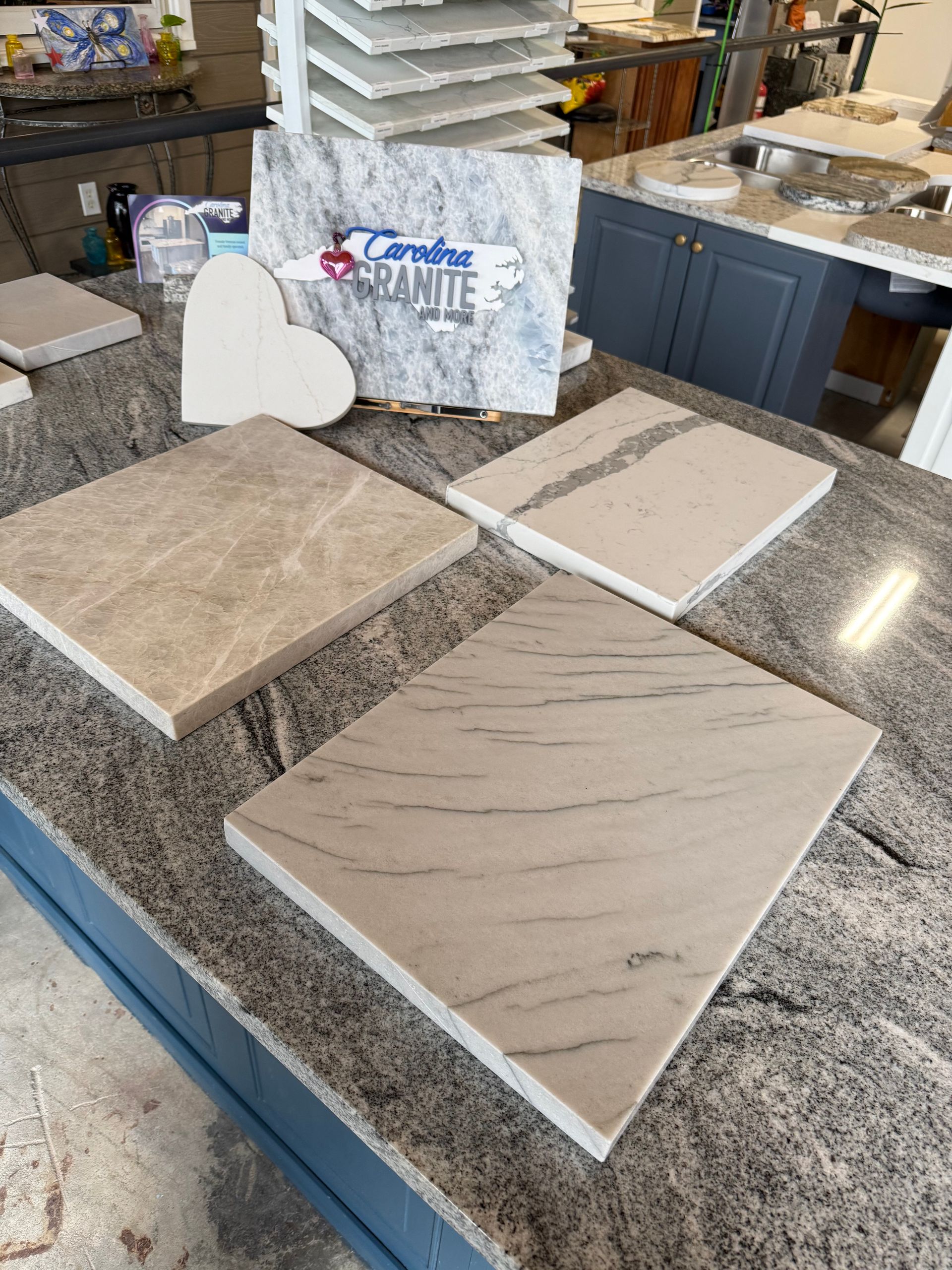 Countertop tile samples displayed on a granite counter in a showroom, with a sign in back.