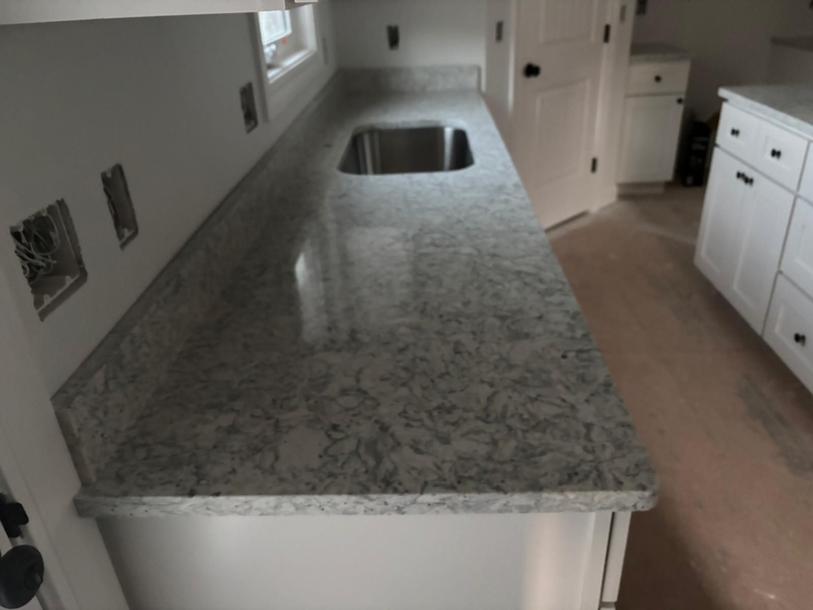 Long granite kitchen island with built-in sink in a bright white kitchen