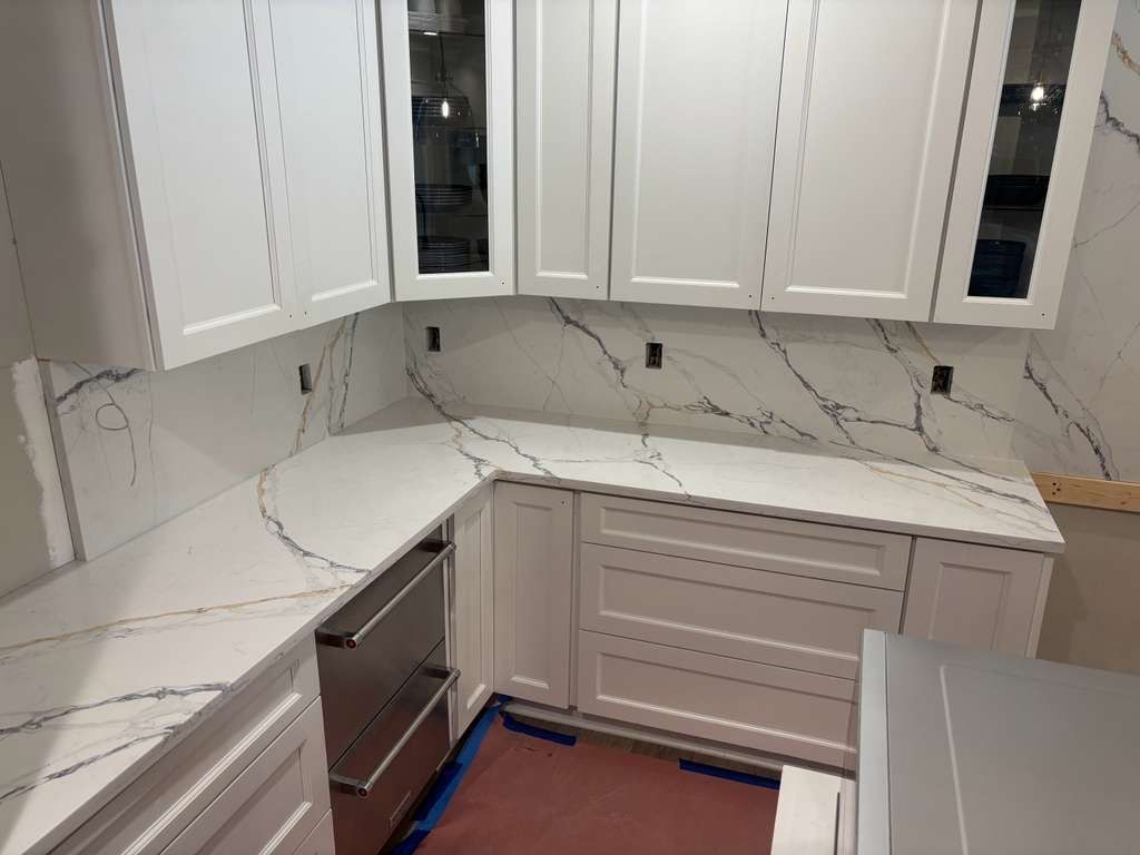 White kitchen with marble-look countertops, corner cabinets, and built-in oven.