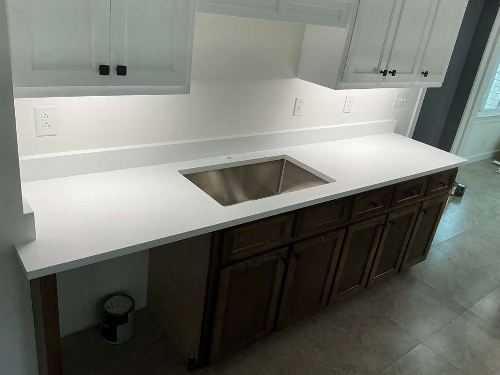 Kitchen counter with white countertop, stainless sink, gray cabinets, and dark lower cabinets.