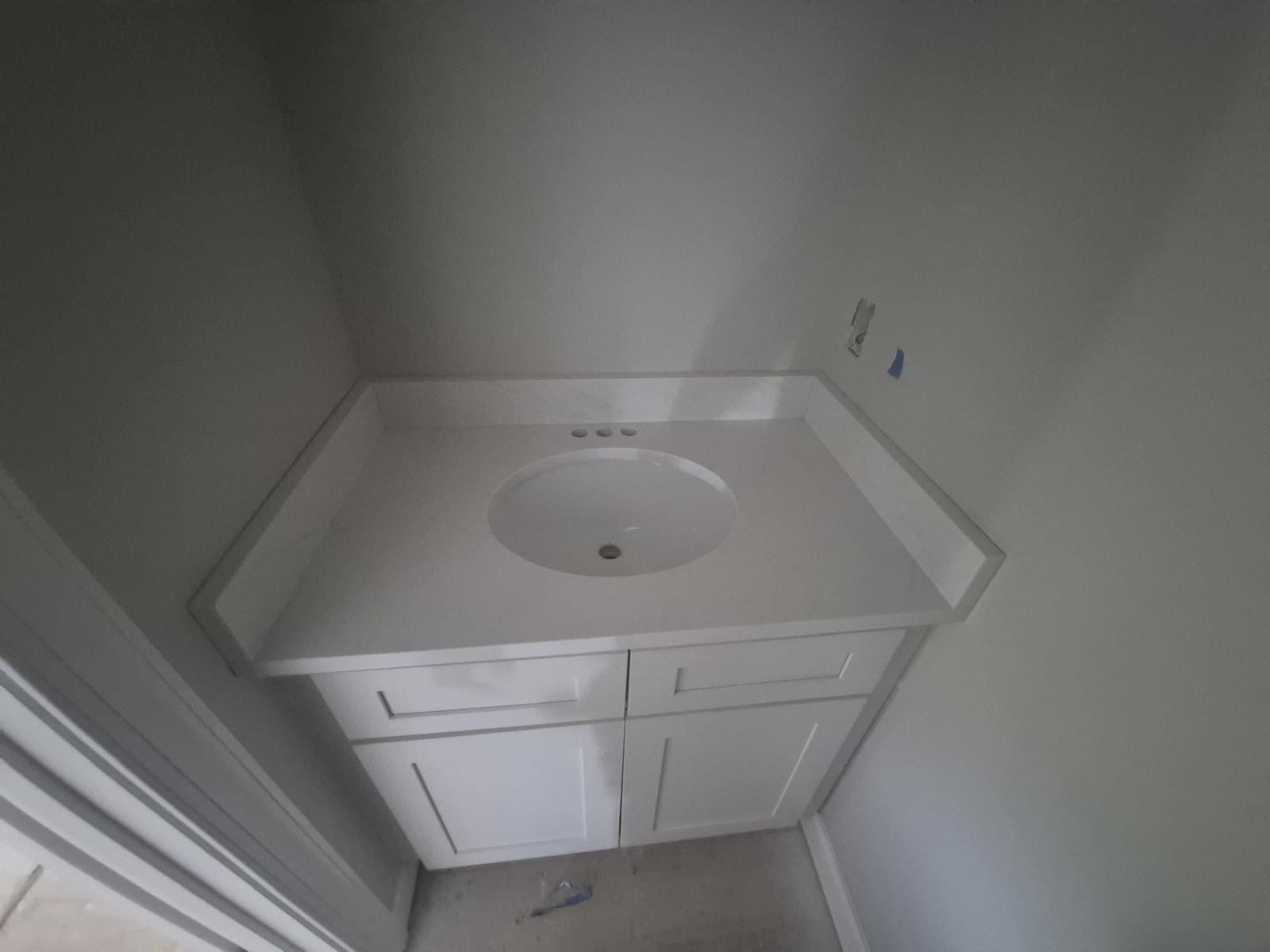 Small bathroom vanity with white sink and cabinet in a narrow alcove