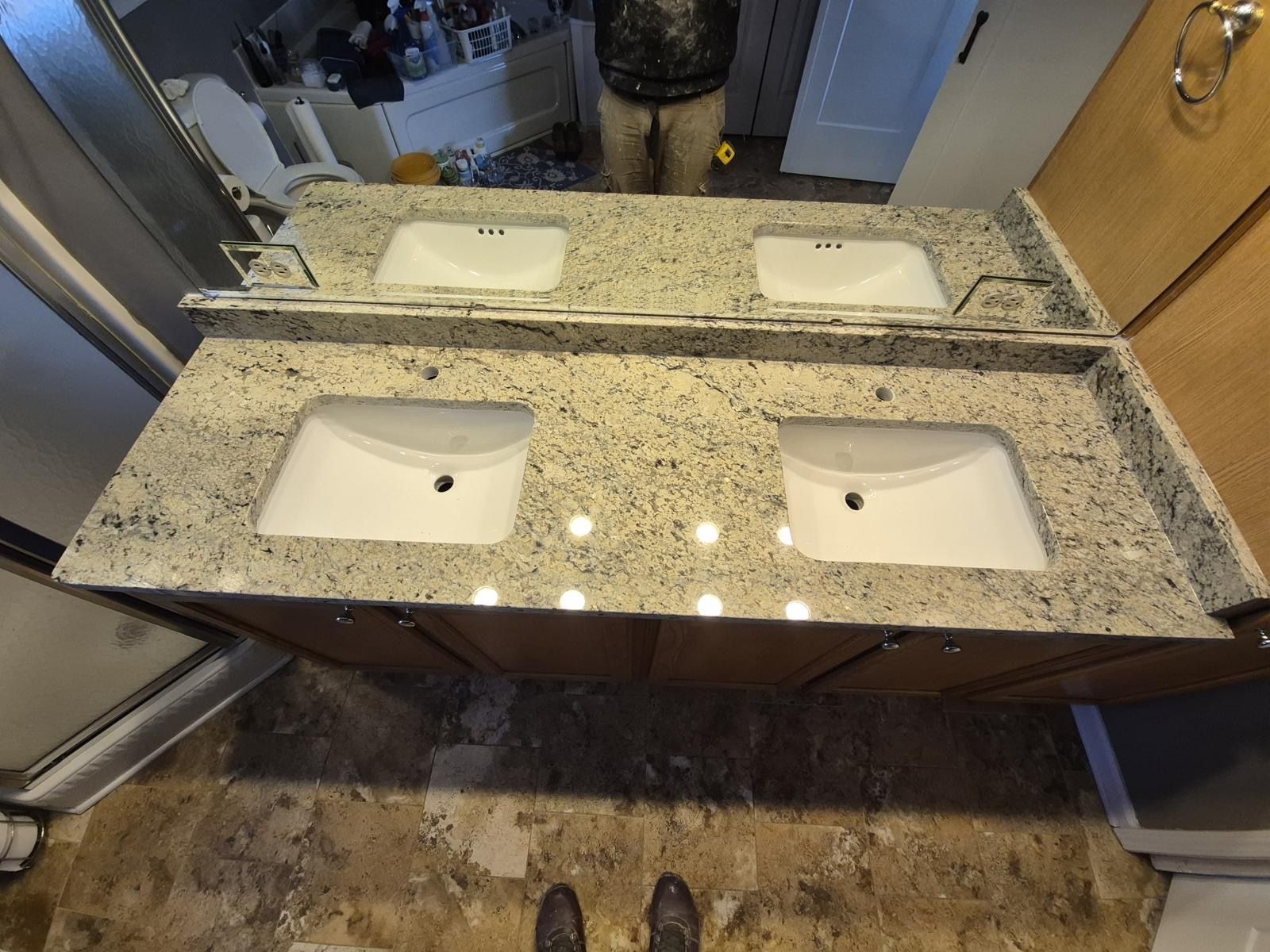 Double bathroom vanity with granite countertop and two white sinks, seen from above