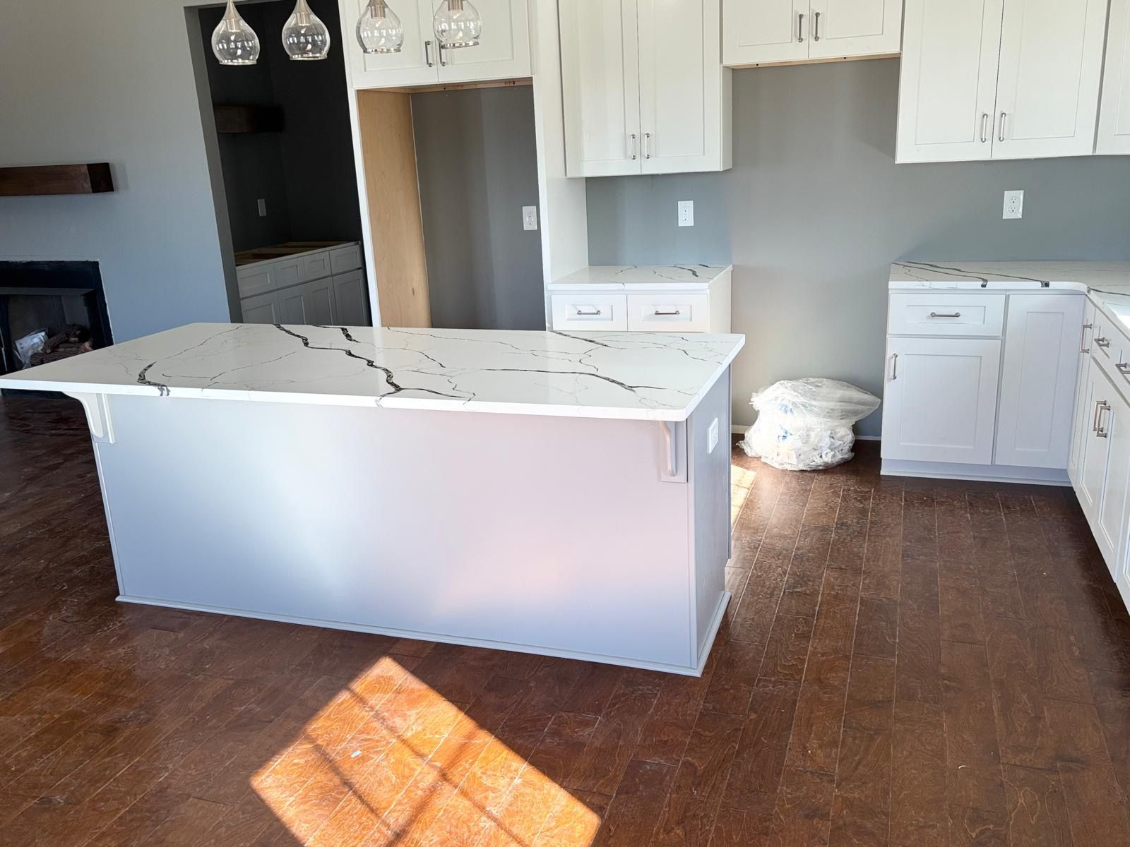 Bright kitchen with white island, gray walls, wood floor, and natural light from a window