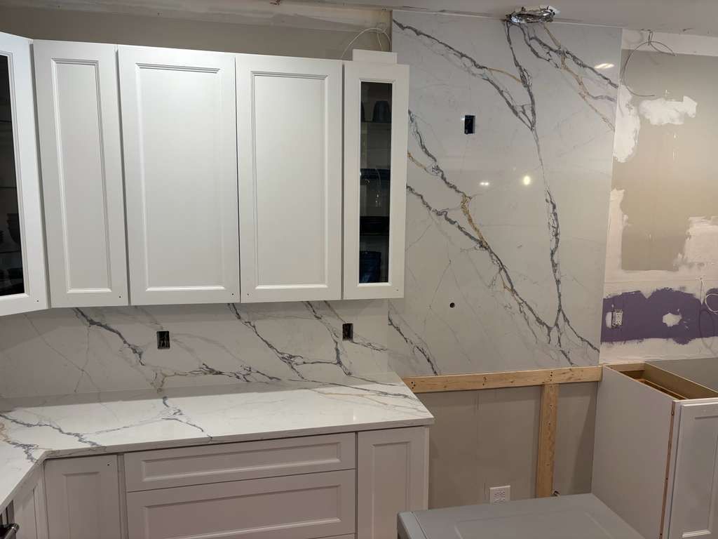 Kitchen cabinets and marble backsplash being installed during a renovation