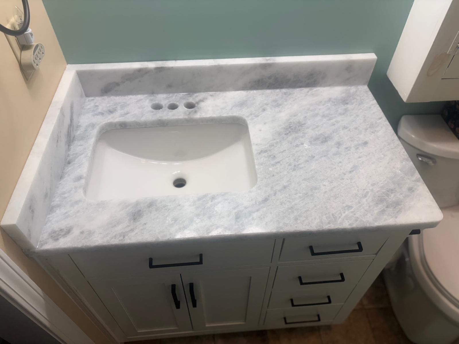 Bathroom vanity with marble countertop, white sink, and drawers beneath