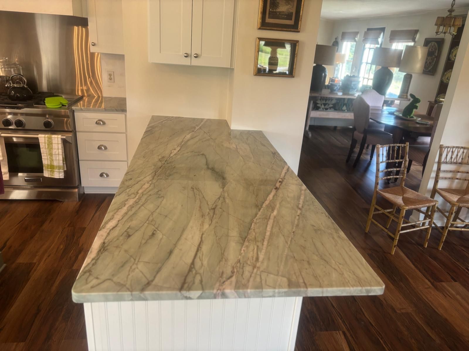 Kitchen island with a veined stone countertop in a bright open-plan kitchen and dining area