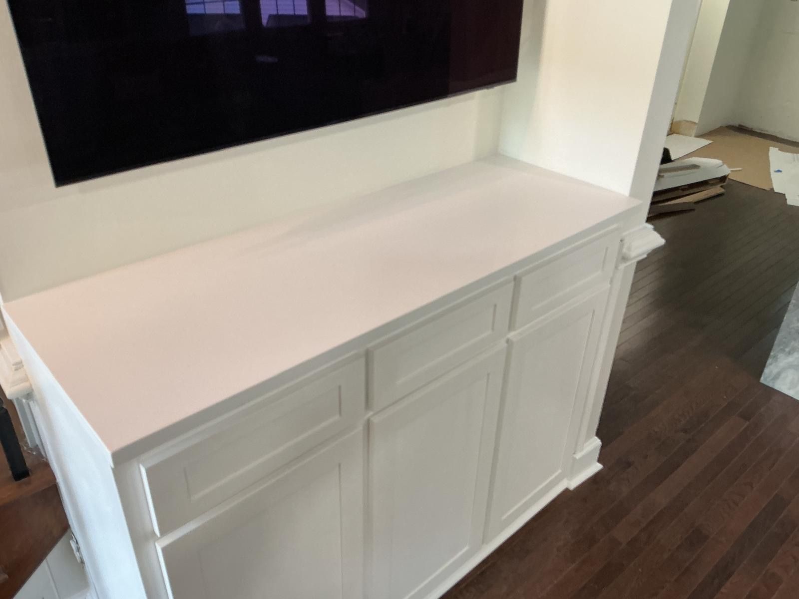White cabinet with a smooth top against a wall in a room with dark wood flooring.