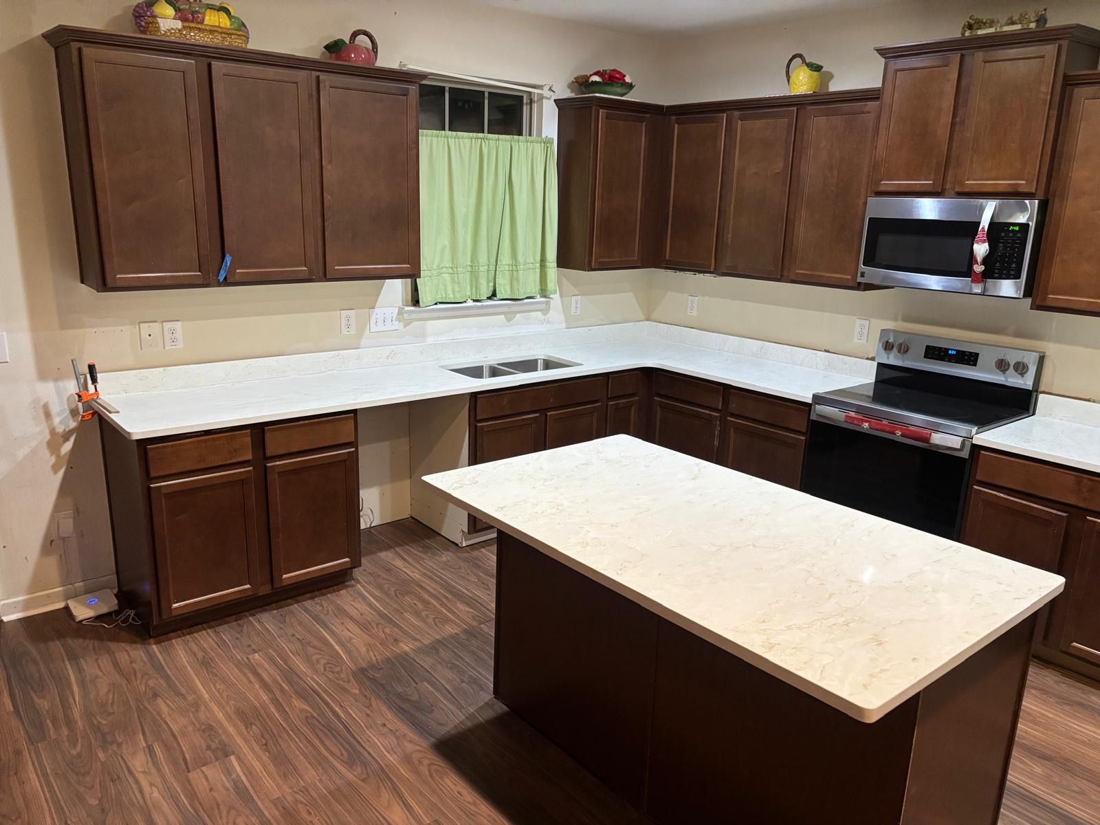 Modern kitchen with dark wood cabinets, white countertops, and a central island in an L-shaped layout