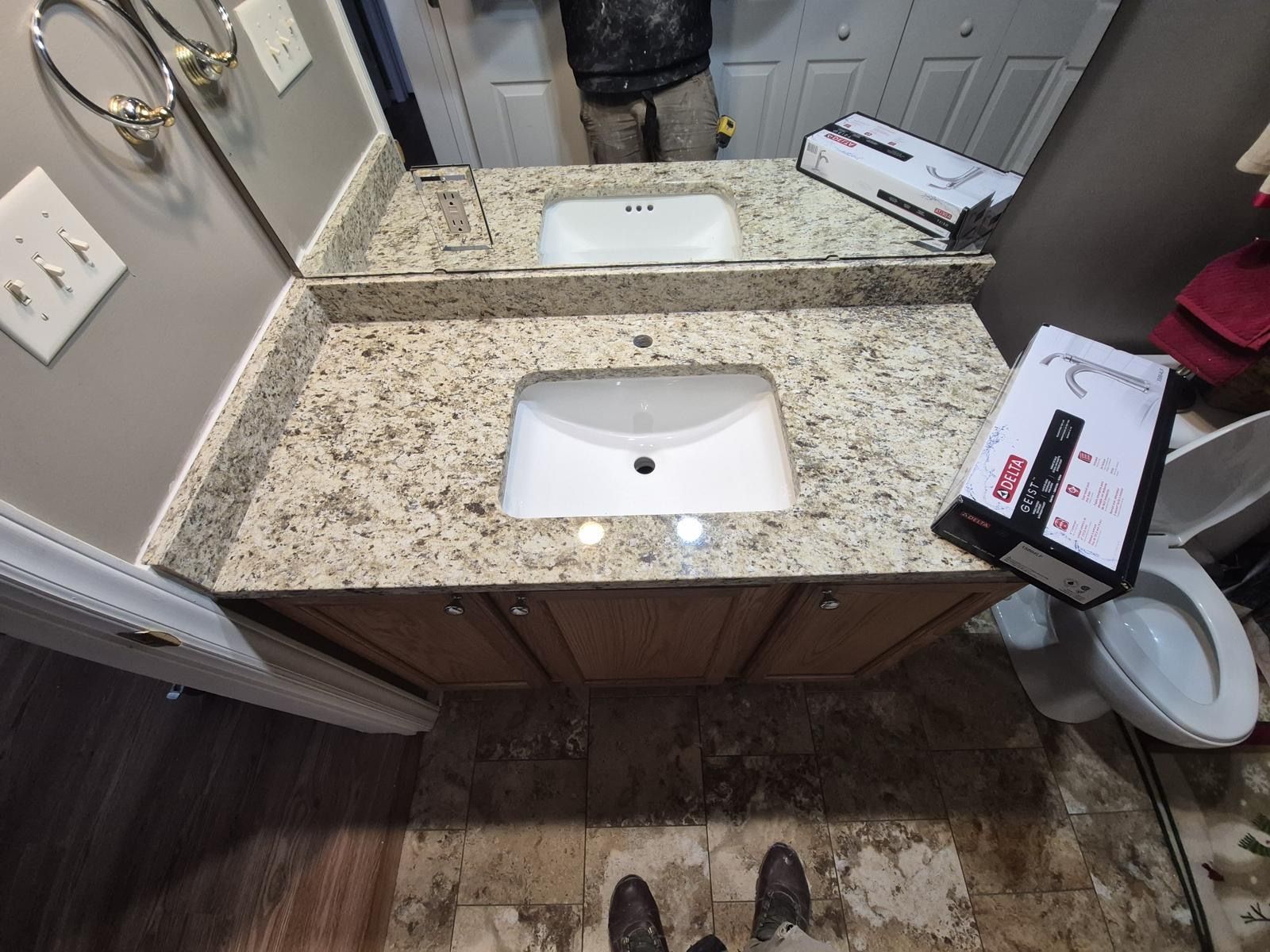 Bathroom vanity with granite countertop, sink, mirror, and a tablet mounted on the right side.