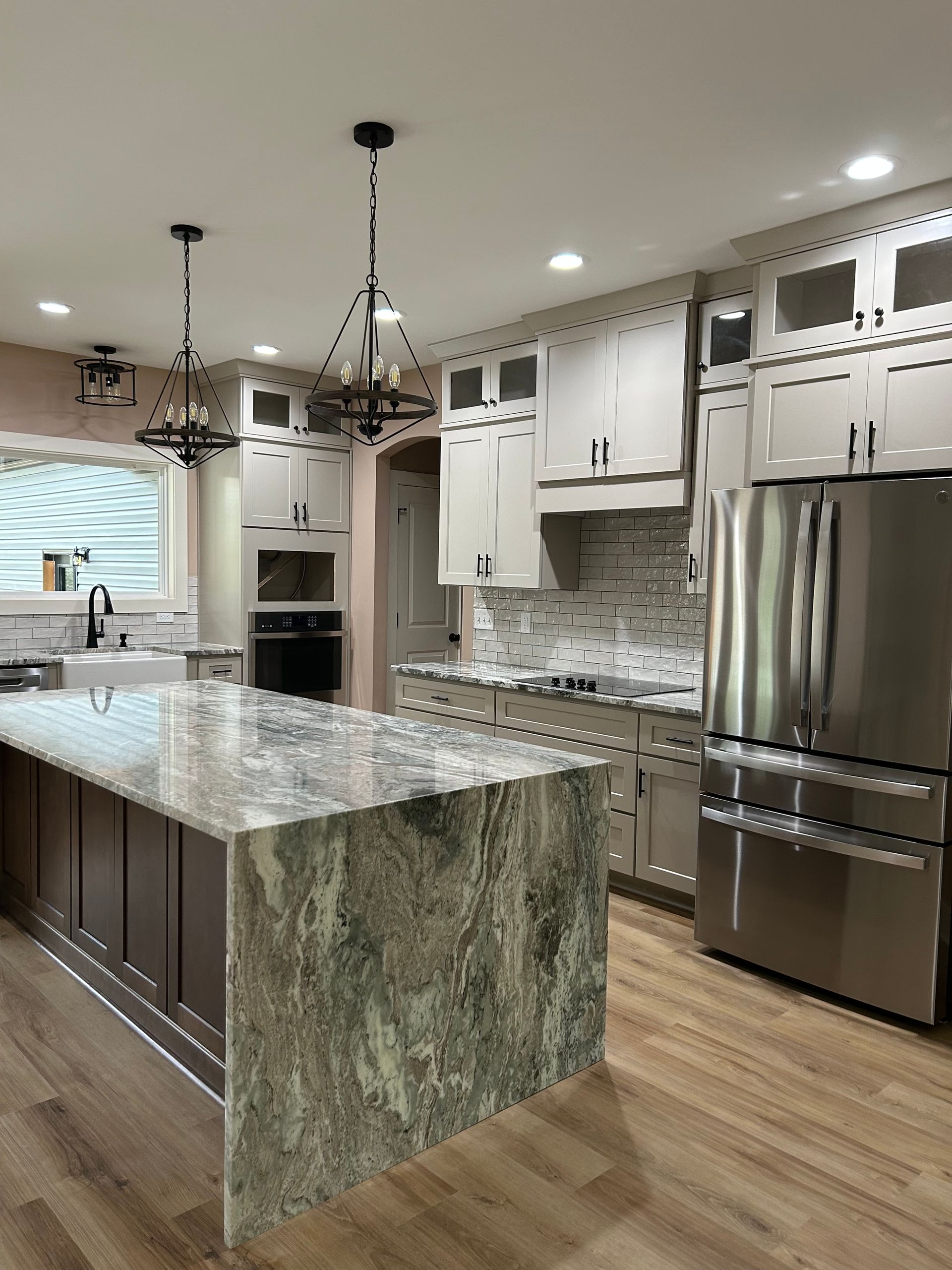 Modern kitchen with granite island, white cabinets, stainless steel appliances, and pendant lights