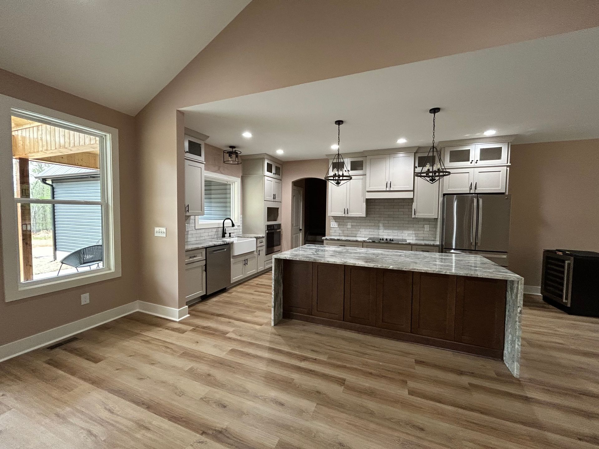 Open kitchen with granite island, white cabinets, and wood floors in a beige living area