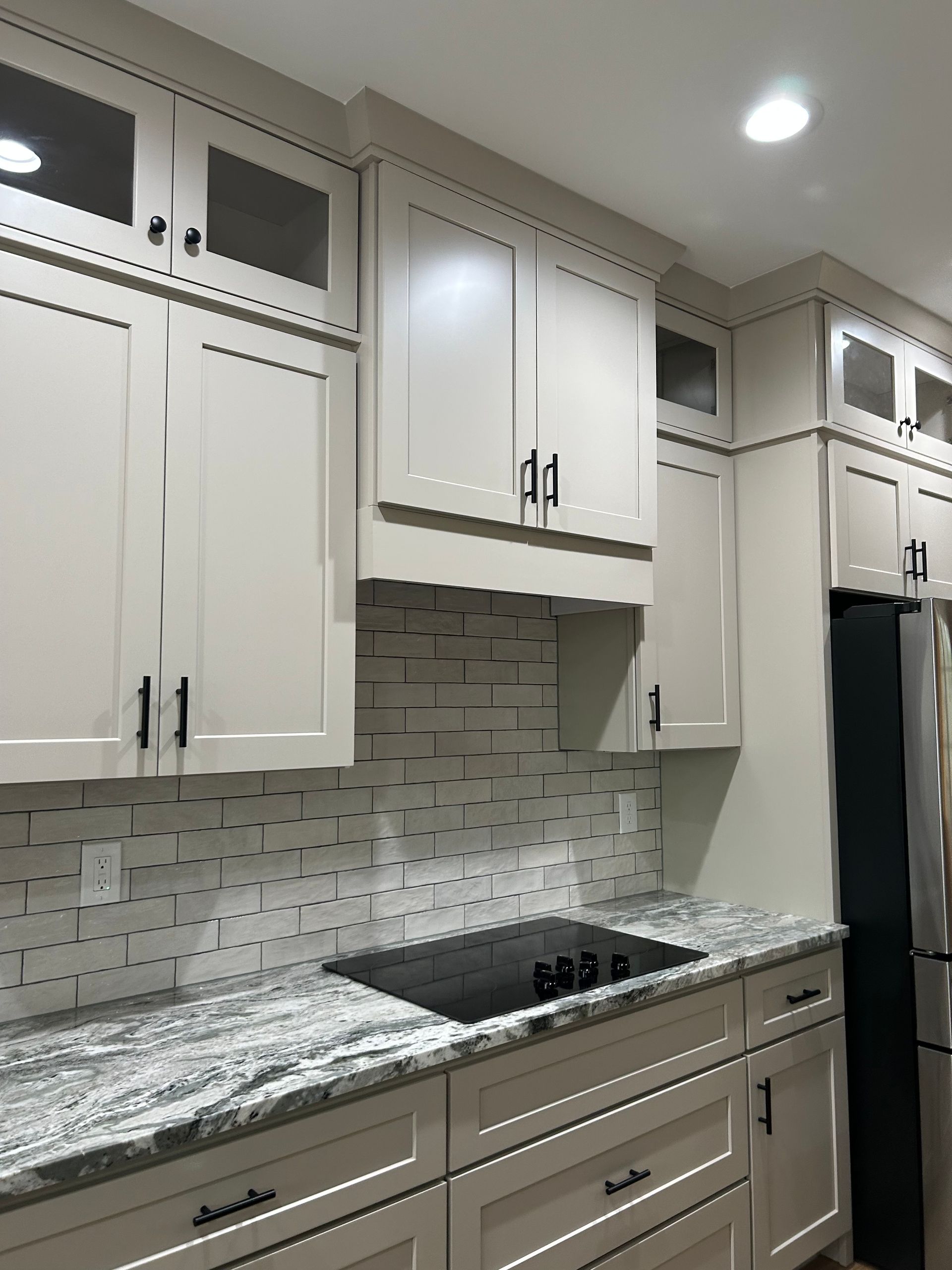 Modern kitchen with white cabinets, gray marble countertops, and a mosaic tile backsplash