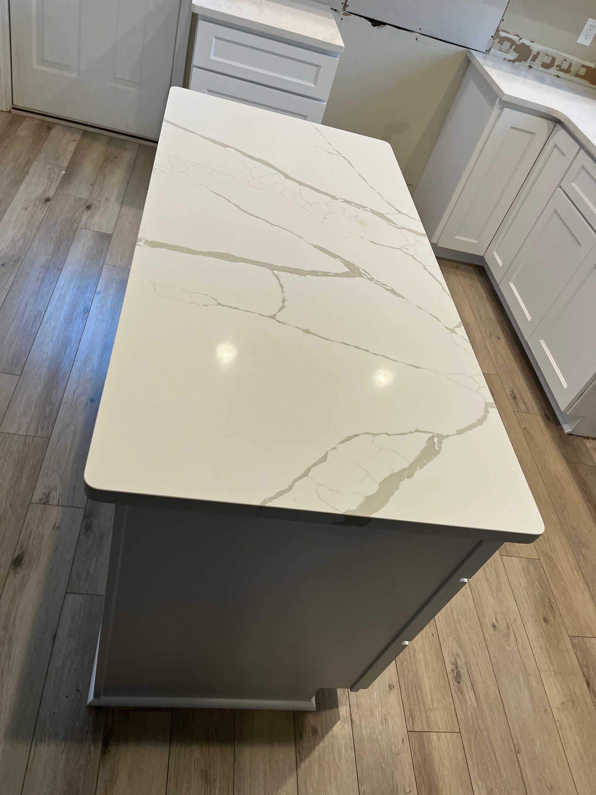 Kitchen island with white marble-look countertop and gray base in a bright kitchen