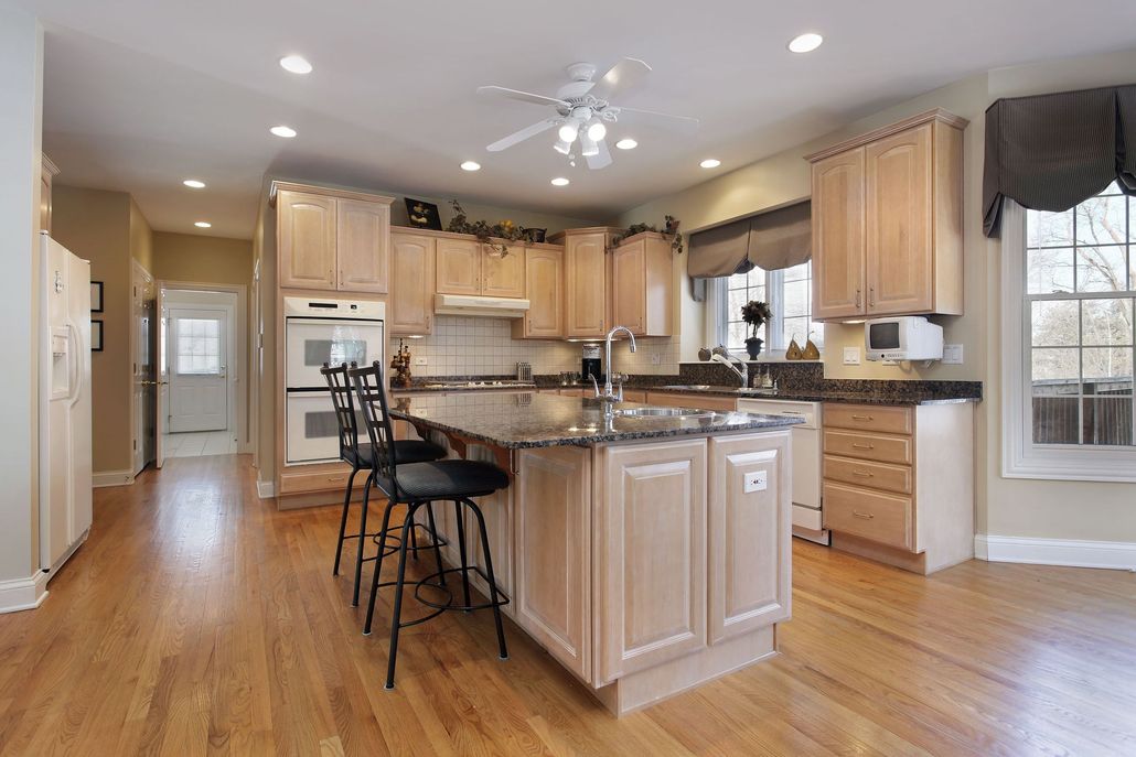 Bright, spacious kitchen with light wood cabinets, island seating, and hardwood floors